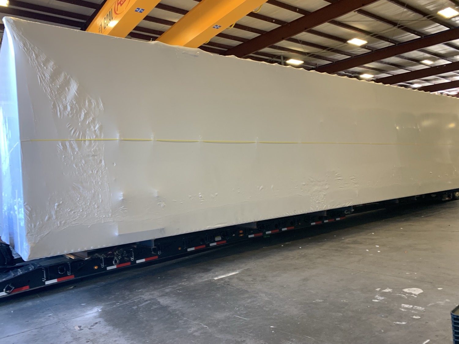 Long equipment trailer wrapped indoors
